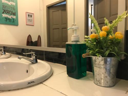 a bathroom sink with a faucet and flowers on a counter at Check In Lodge in Kuching