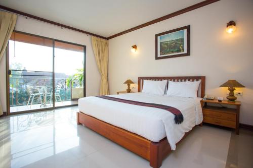 a bedroom with a large bed and a large window at Baankhun Chiang Mai Hotel in Chiang Mai