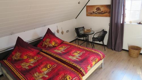 クサンテンにあるPrivatzimmer Lüttingenのベッドルーム1室(赤いシーツとテーブル付きのベッド1台付)