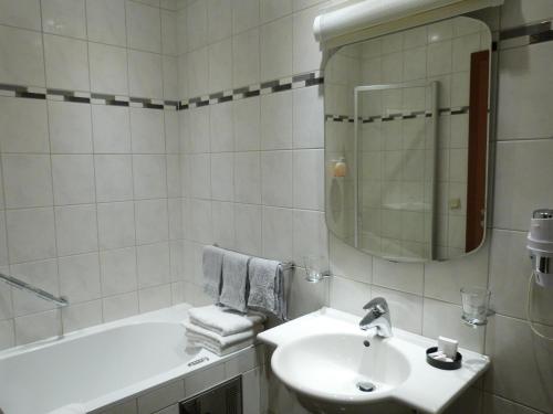 a white bathroom with a sink and a bath tub at Hôtel - Restaurant " Victor Hugo" in Vianden
