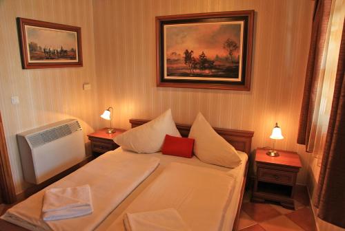 a small bedroom with a bed and two night stands at Berényi Fogadó in Nagykanizsa