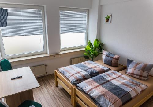 a bedroom with a bed and two windows at BoardingHouse Quickborn in Quickborn