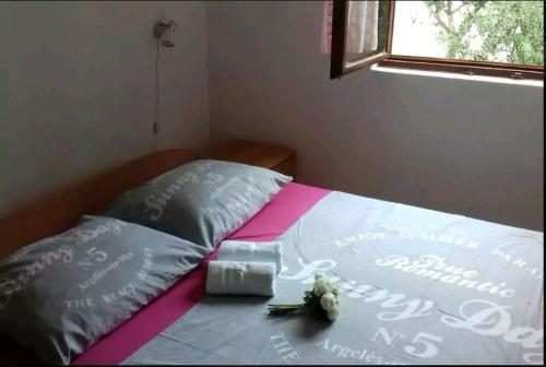 a bed with two pillows and a box on it at Jelena Holiday House in Karlobag