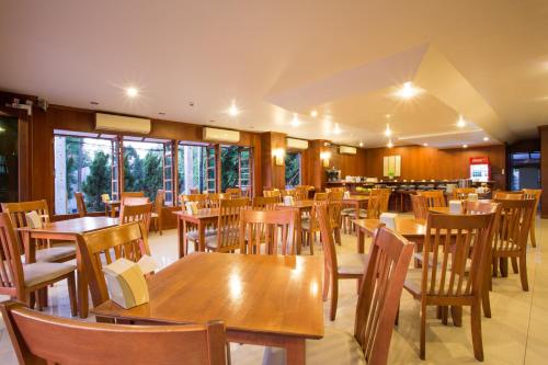 une salle à manger avec des tables et des chaises en bois dans l'établissement Baankhun Chiang Mai Hotel, à Chiang Mai