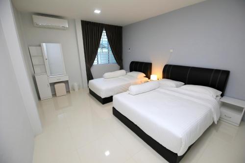 2 camas en un dormitorio con paredes blancas y suelo blanco en 722 Homestay, en Kuching