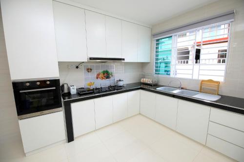 cocina blanca con armarios blancos y ventana en 722 Homestay, en Kuching
