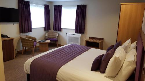a hotel room with a large bed and windows at Weald of Kent Golf Course and Hotel in Maidstone