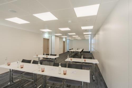 a large room with white tables and chairs at HOTEL illuster - Urban & Local in Uster