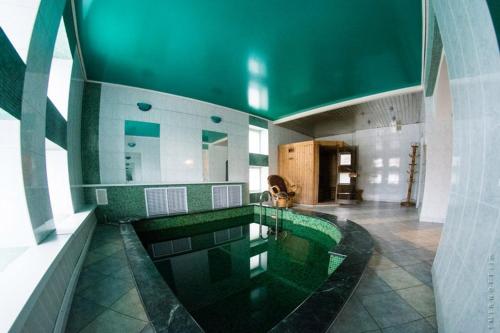 a swimming pool in a building with a green ceiling at Gostevoy Dom Hotel in Rybinsk