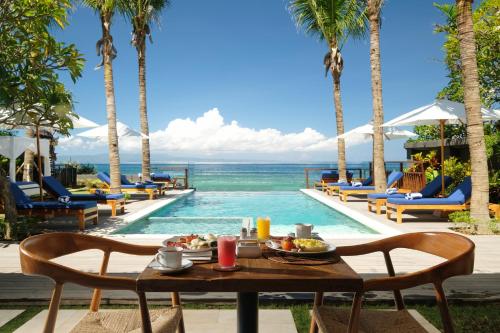 a table with food next to a swimming pool at Sagara Candidasa by AHM in Candidasa