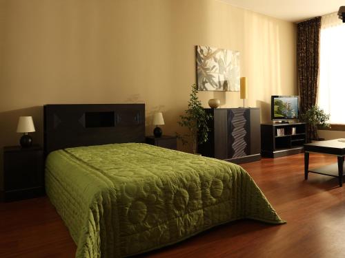 a bedroom with a bed with a green bedspread at Apartamenty Złota Nić in Opole