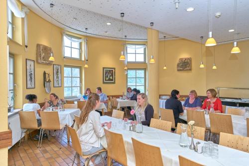 a group of people sitting at tables in a restaurant at Ev.Familienferien-und Bildungsstätte Ebernburg in Bad Münster am Stein-Ebernburg