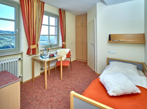 Habitación de hotel con cama, escritorio y ventana en Ev.Familienferien-und Bildungsstätte Ebernburg en Bad Münster am Stein-Ebernburg