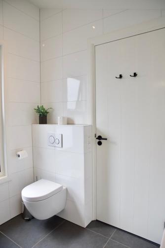 a white bathroom with a toilet and a door at Het Torentje aan de IJssel in Montfoort