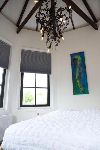 a bedroom with a white bed and a chandelier at Het Torentje aan de IJssel in Montfoort