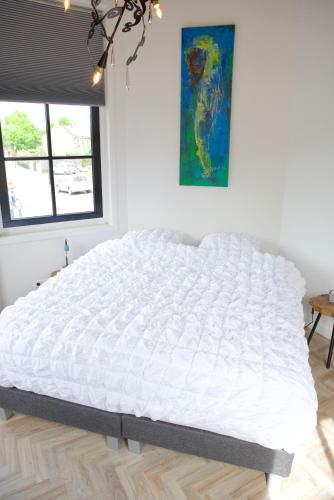 a large white bed in a room with a window at Het Torentje aan de IJssel in Montfoort