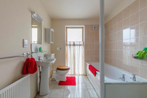 e bagno con lavandino, servizi igienici e vasca. di Sutton Cottage a Wexford