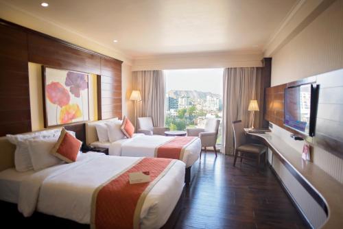 Habitación de hotel con 2 camas y TV de pantalla plana. en Shakun Hotels And Resorts en Jaipur