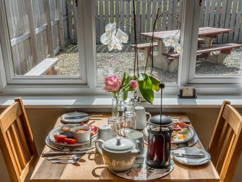 einen Tisch mit Teller mit Lebensmitteln und Blumen darauf in der Unterkunft The Birches in Dingwall