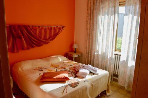 a bedroom with a bed with orange walls and a window at Suites Piazza Umberto in Vignacastrisi