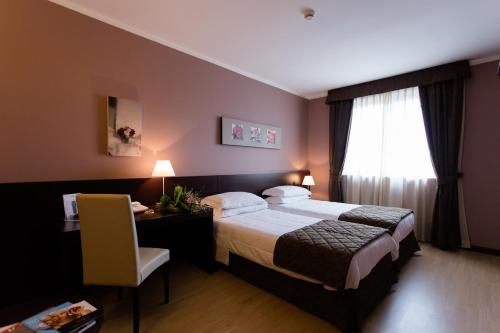 a hotel room with a bed and a desk and a window at Air Palace Hotel in Leinì