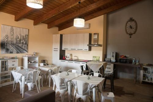 un restaurante con mesas y sillas blancas y una cocina en Room & Breakfast Le Magie, en Sindia
