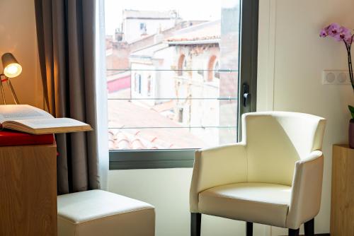 a room with a chair and a window at Hôtel Le Père Léon in Toulouse