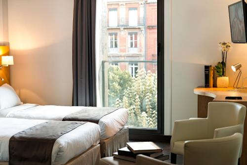a hotel room with two beds and a window at H&ocirc;tel Le P&egrave;re L&eacute;on in Toulouse