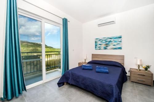 a bedroom with a bed and a large window at Hillock Residence Apartments in Marsalforn