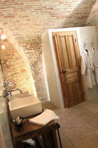 a bathroom with a sink and a mirror and a door at Le Mas de l'Espérance - Chambres d'hôtes de Prestige in Garons