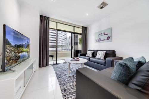 a living room with a couch and a tv at York Apartments on Grenfell in Adelaide