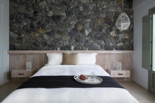a bedroom with a bed with a stone wall at Melograno Villas in Astypalaia Town