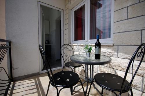 a table with a bottle of wine and two chairs at Apartment Ivan in Kastel Sucurac