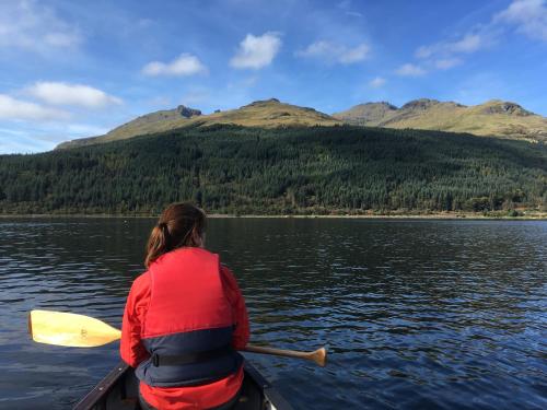 a woman is paddling a canoe on a lake at Mansefield House in Arrochar