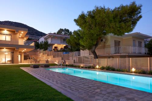a house with a swimming pool in front of a house at Elaia Luxury Suites Lagonisi in Lagonissi