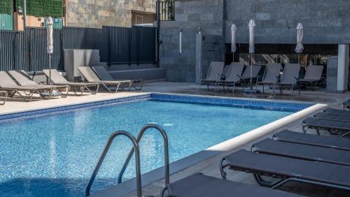 a swimming pool with chaise lounge chairs next to it at Rosamar Es Blau 4*s - Adults Only in Lloret de Mar