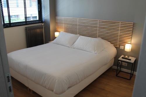 ブローニュ・ビヤンクールにあるAppartements Paris Boulogneのベッドルーム(白い大型ベッド、ランプ2つ付)