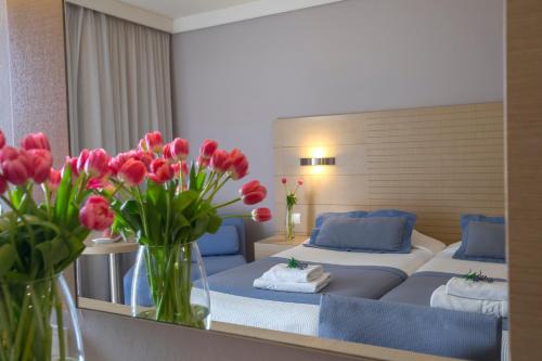 a bedroom with two beds and vases of red flowers at Louis Ledra Beach in Paphos City