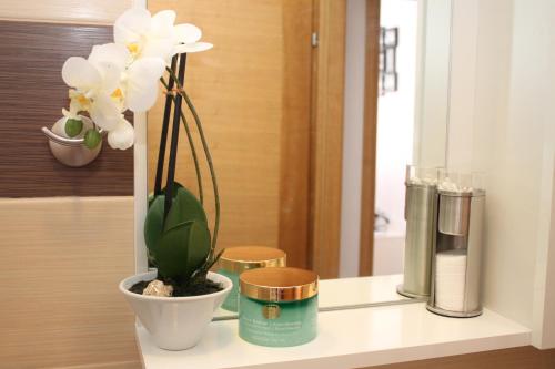 a white vase with a plant on a table at Apartman Bombon in Selce