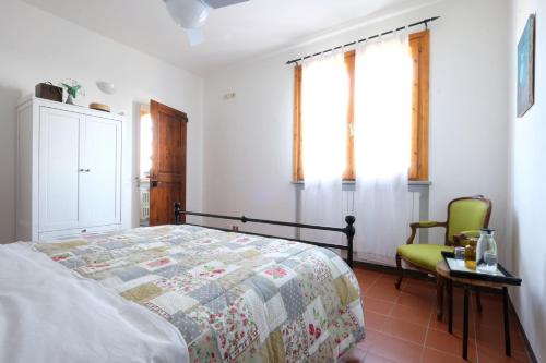 a bedroom with a bed and a chair and windows at Casa Monteluro - B&b in Tavullia