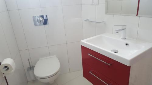 a white bathroom with a toilet and a sink at Apartament Centrum 2 in Mikołajki