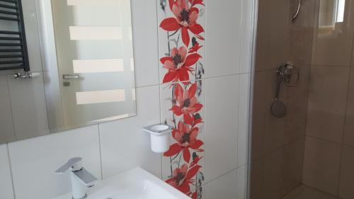 a bathroom with a red flower pattern on the wall at Apartament Centrum 2 in Mikołajki