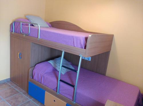 ラス・ネグラスにあるBonito apartamentoの紫のシーツが備わる客室の二段ベッド2台