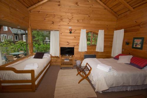 1 dormitorio con 2 camas en una cabaña de madera en Cabañas Playa Linda, en Pucón