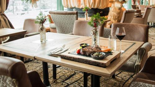 a table with a plate of food and a glass of wine at Bachleda Hotel Kasprowy in Zakopane