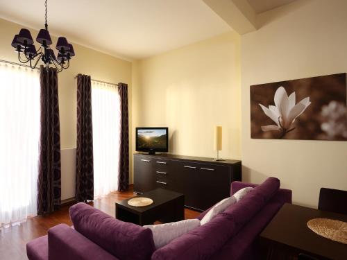 a living room with a purple couch and a tv at Apartamenty Złota Nić in Opole
