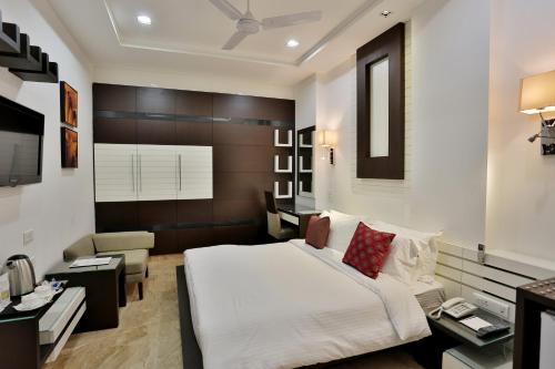 a bedroom with a large white bed and a desk at Hotel D'PRESIDENTE in New Delhi