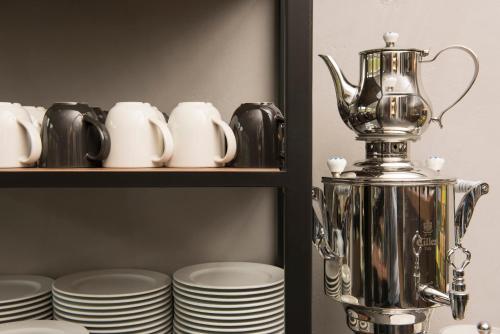 a silver pitcher on a shelf with plates at ibis Styles Hotel Gelsenkirchen in Gelsenkirchen