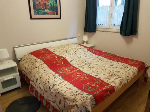 a bed with a red and white blanket on it at Les Dames de la Montagne in Frauenberg
