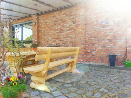 a wooden bench sitting in front of a brick wall at Radlerhof Spreewald in Kolkwitz